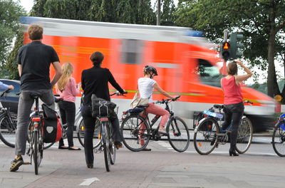 Rear view of people cycling on street