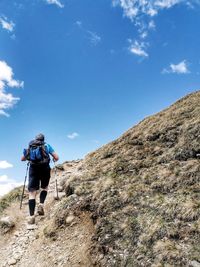 Rear view of man climbing on mountain against sky