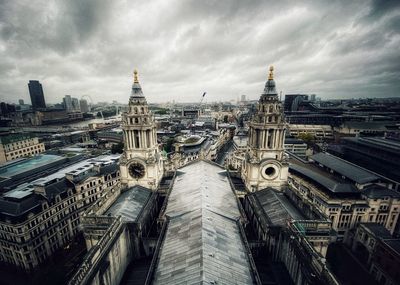 Aerial view of city buildings against cloudy sky