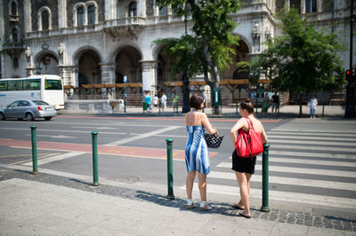Full length of women standing on sidewalk in city