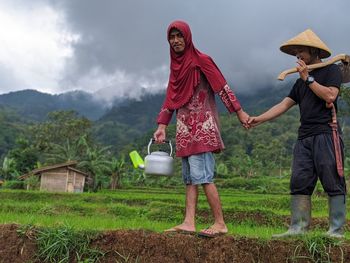 Man and woman standing on land by mountain against sky