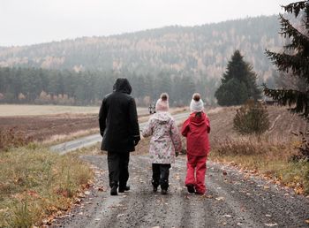 Rear view of mother with daughters on footpath