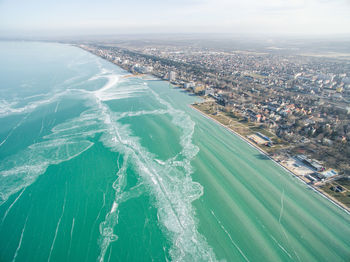 High angle view of city by harbor at frozen river