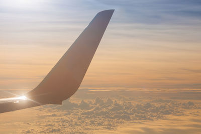 Airplane wing against sky during sunset