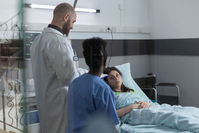 Portrait of patient looking at doctor lying on bed