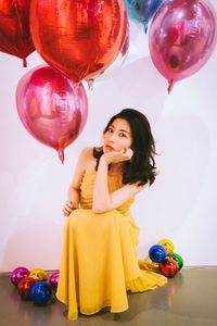 Happy young woman with balloons against gray background