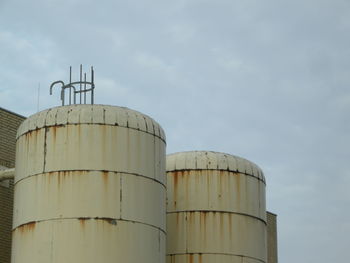 Low angle view of industry against cloudy sky