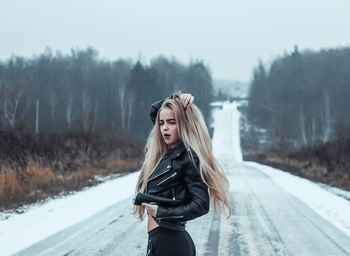 Young woman posing while standing on snow covered road
