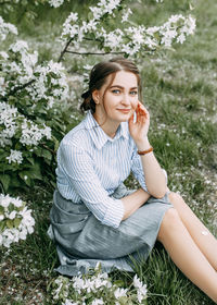 Portrait of smiling young woman sitting against plants