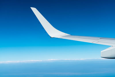 Wing of plane over white clouds. airplane flying on clear blue sky. scenic view from airplane window
