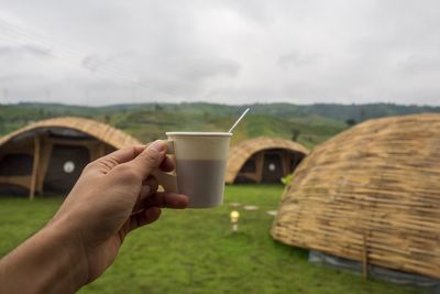 Close-up of hand holding drink in field