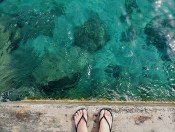 Low section of woman standing against sea