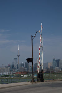 Street light by road against buildings in city against sky