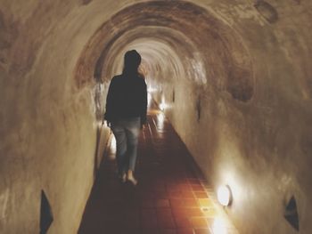 Rear view of man walking in tunnel
