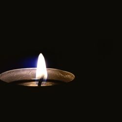 Close-up of lit candle in darkroom