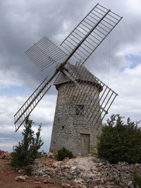 Low angle view of windmill on field against sky