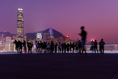 Tourists visit hong kong seaside viewpoint at twilight, ifc tower, a landmark on hong kong island