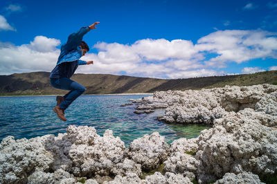 Man jumping in sea against sky