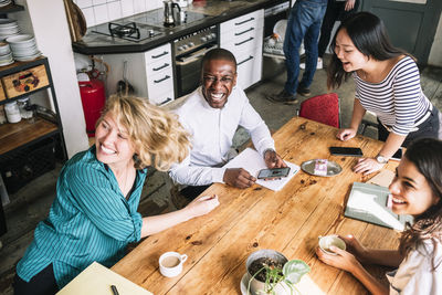 High angle view of cheerful computer hackers enjoying at table in creative office