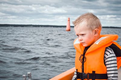 Boy looking at sea against sky