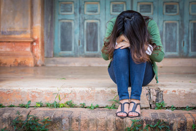 Full length of woman sitting outdoors