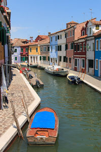 Boats moored on canal by colorful buildings at burano island