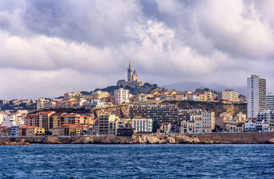 View of buildings in city against cloudy sky