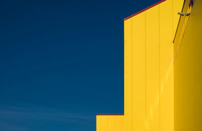 Low angle view of yellow house against clear blue sky
