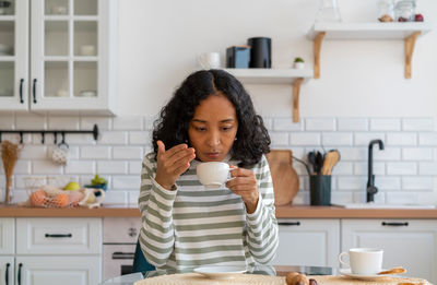 Portrait of young woman having food at home