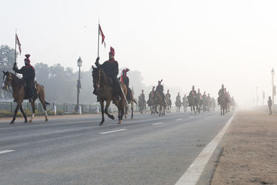 Indian soldiers riding horses on street against clear sky on the eve of republic day.