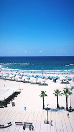 Aerial view of people at beach against blue sky during sunny day