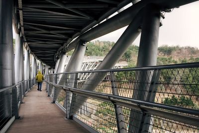 Rear view of man walking on bridge
