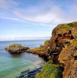 Rocks on shore by sea against sky