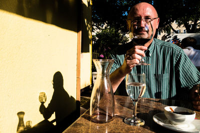 Mature man having red wine at outdoor restaurant on sunny day