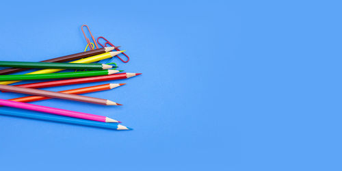 High angle view of colored pencils on table against blue background