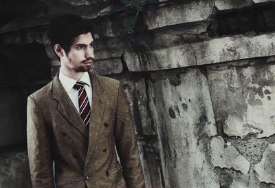 Thoughtful man in businesswear standing by abandoned wall