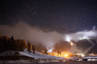 Scenic view of snow covered mountains against star field at night