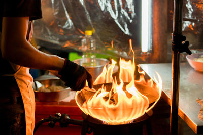 Midsection of chef preparing food in commercial kitchen