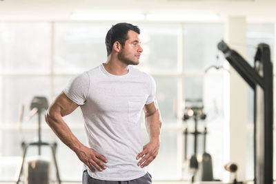 Muscular man looking away while standing in gym