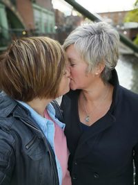 Lesbian couple kissing outdoors while standing in city