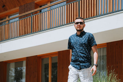 Portrait of young man standing against built structure