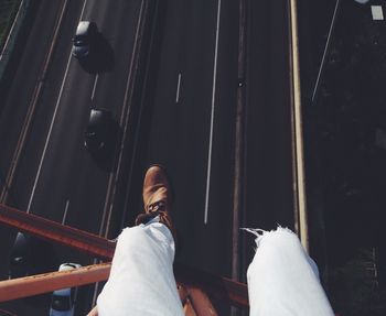 Low section of man sitting on bridge over road