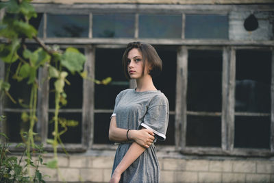 Portrait of young woman standing against windows