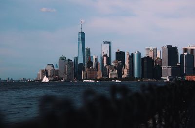 Modern buildings by river against sky