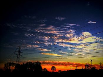 Low angle view of electricity pylon at sunset