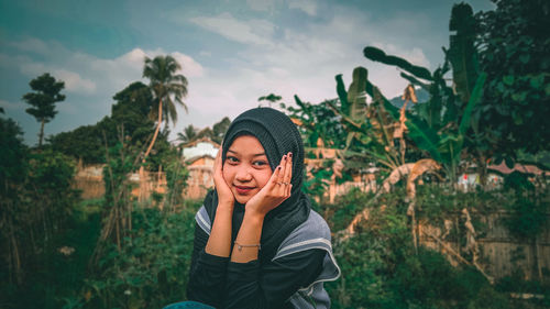 Portrait of smiling young woman standing against plants