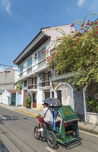 Bicycles on street by buildings against sky