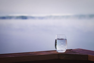 Close-up of glass on table against sea
