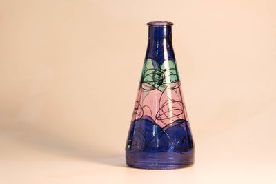 Close-up of glass bottle on table against wall