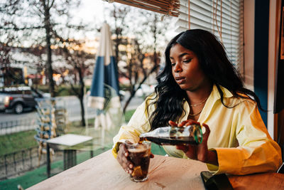 Young woman looking away while sitting on table